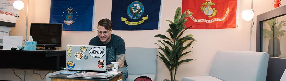 A veteran student sits smiling inside of a veterans center at a Pima campus